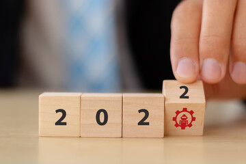 New year 2022, futuristic and digital trends concept with robotic technology. Hand flips wooden cubes with robot symbol and 2022 letters on smart background. Innovation, digital technology plan banner