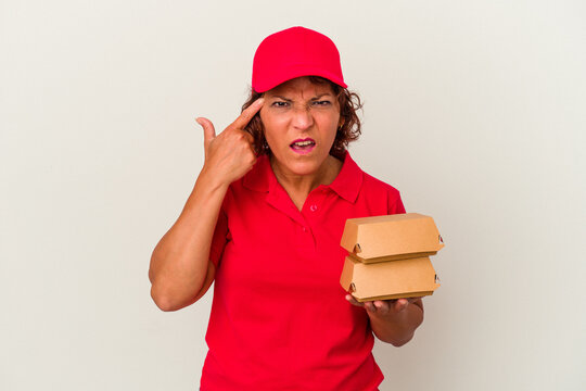 Middle age delivery woman taking burguers isolated on white background showing a disappointment gesture with forefinger.