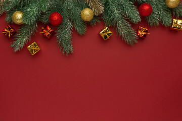 Naklejka na ściany i meble Christmas composition. Coniferous branches and decorative ornaments on a red background.