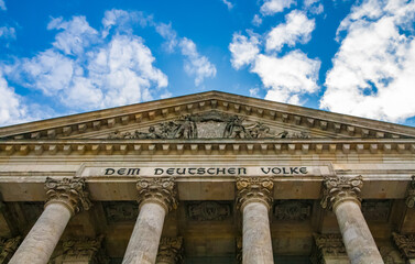 Fototapeta premium Great low-angle view of the inscription Dem Deutschen Volke, meaning To the German people, on the frieze between the columns and the pediment of the Reichstag building in Berlin, Germany.