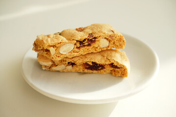 Cantucci cookies with candied fruits and nuts on a white plate. White background