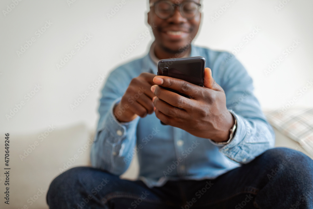 Fototapete cropped shot of an black man using a smartphone while sitting indoors. cropped shot of an handsome b
