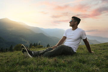 Naklejka na ściany i meble Handsome man enjoying beautiful mountain landscape at sunset