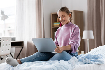 children, education and learning concept - happy smiling student girl with laptop computer at home