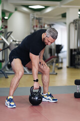 Fototapeta na wymiar Sporty Caucasian man lifting the kettle bell during workout in the gym. Sport and health concept