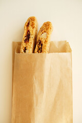Cantucci cookies with candied fruits and nuts in a paper bag. White background