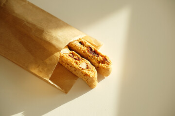 Cantucci cookies with candied fruits and nuts in a paper bag. White background, sunlight
