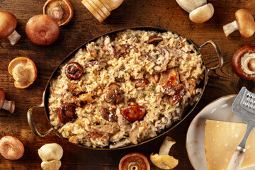 Risotto ai funghi, mushroom risotto, rustic rice with mushrooms and cheese, overhead shot on a dark wooden background with ingredients