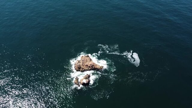 Drone steady video of a rock in the middle of the ocean.