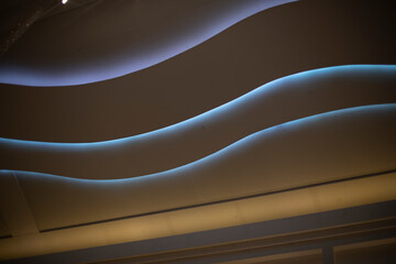 Ceiling in the mall. Light in the big interior. Lamps in the form of a wave on the ceiling.