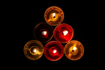 The candles are laid out in a triangle. Candles burn in the dark. Red and yellow wax.