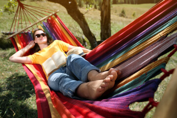 Woman resting in hammock outdoors, focus on legs