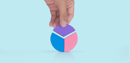 Business connecting piece of multi colored pie wood chart in hand