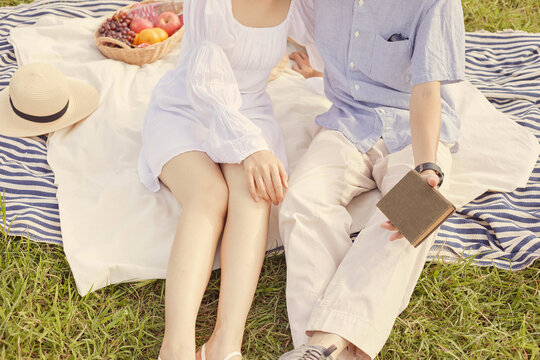 picnic concept The woman with white skirt and sandals sitting beside the man who puts on beige pants and grey sneakers
