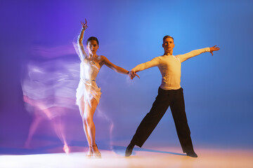 Fototapeta premium Dynamic portrait of graceful dancers, flexible man and woman dancing ballroom dance isolated on gradient blue purple background in neon mixed light