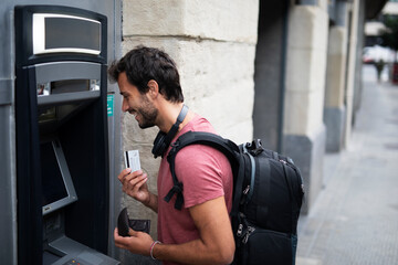 Young man withdrawing money from credit card. Man typing pin code on keypad of ATM machine.