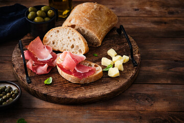 Cured Meat and ciabatta bread on wooden board, rustic style.