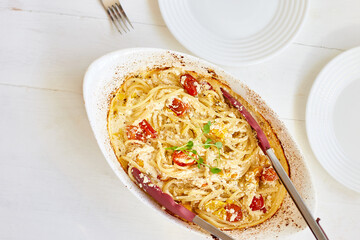 Trending viral recipe of baked tomatoes and feta with pasta, Fetapasta on a white wooden background