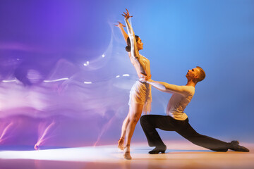 Jeunes danseurs gracieux, homme et femme flexibles dansant danse de salon isolés sur fond violet bleu dégradé en lumière mixte néon