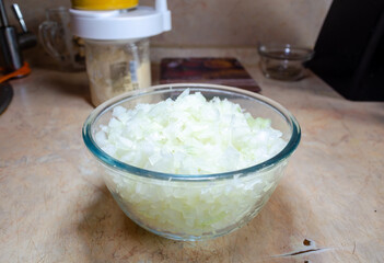 finely cut onions in a glass bowl on a light pink table