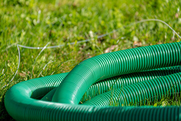 Selective focus of green plastic pipe in the garden, Stack of tubing on green grass meadow,...