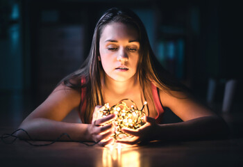 Woman with christmas light. Hope, despair and emotion. Portrait of a model with beautiful face in...