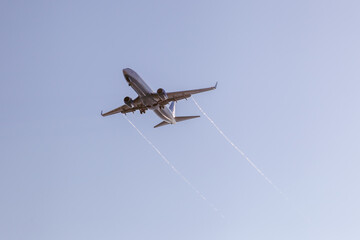 the plane flies against the background of the blue sky