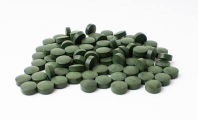 Lots of scattered green pills on a white background.