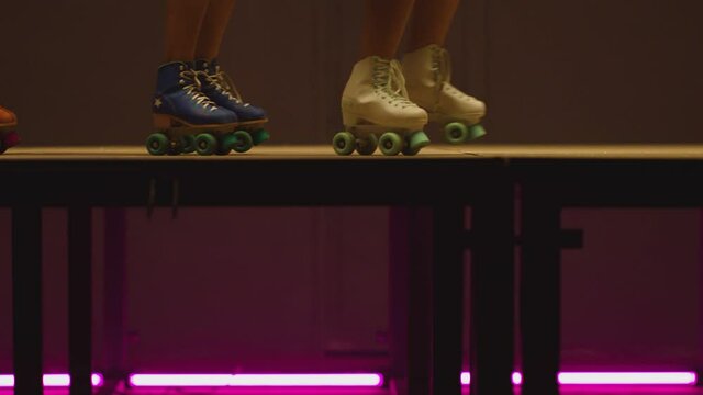4K Female legs in roller blades, skating fast at the roller park on floor . Close-up legs of young women is professionally skating . Different kind of and colorful vintage  roller blades . Slow Motion