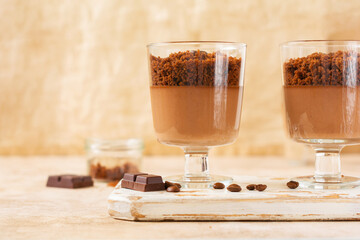 Delicious dessert chocolate mousse with brownie in glass jars on a light slate, stone or concrete background. Selective focus