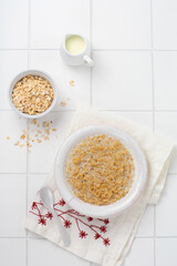 Simple oatmeal porridge with strawberries in a white plate on a linen napkin. Breakfast health food concept. Top view