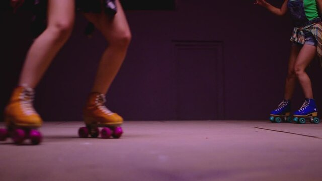 4K Female legs in roller blades, skating fast at the roller park on floor . Close-up legs of young women is professionally skating . Different kind of and colorful vintage  roller blades . Slow Motion