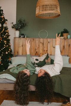 Happy young woman with cute teenage daughter in christmas interior on bed