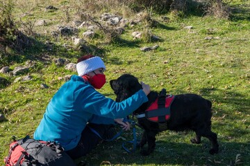 A girl and her dog go hiking in the mountains. Black cocker 