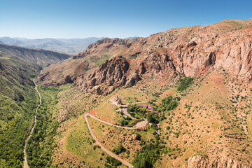 Aerial drone view over an epic gorge in a river valley with red geological rocks. Shot in the area of the Noravank Monastery in Armenia
