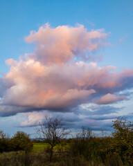Obraz na płótnie Canvas Colored clouds in blue sky over autumn landscape