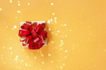 Banner with a Gift box, with a bright shiny red bow on a bright orange (yellow) background. Present for birthday, christmas, new year. Festive concept.