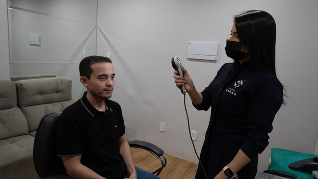 woman doing examination on man with microscope photofinder device in medical clinic on front