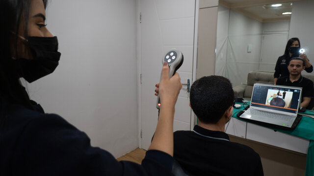 woman doing examination on man with microscope photofinder device in medical clinic