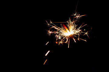 Fototapeta premium One bengal fire sparkles against the black background.