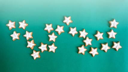 Classic star shape ginger cookies with sugar icing on green background. Christmas treat banner