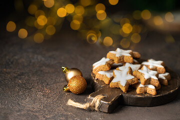 Star shape ginger cookies with sugar icing son wooden cut board with gold bokeh.Copy space