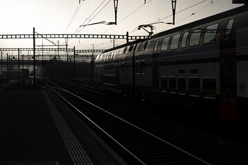 Obraz premium Brouillard dans la gare de Romont en Suisse, photo en contre jour avec les voies et les poteaux.