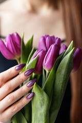 Obraz na płótnie Canvas Girl with a beautiful violet manicure cat eye holding a purple tulips
