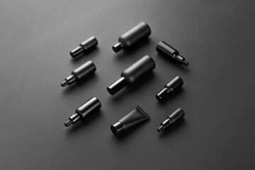 Naklejka premium Cosmetics packaging branding mockup template black moody feel, dropper, dispenser black bottles, packaging, and branding items. Blank isolated on a black background to place your design. 