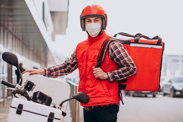 Food delivery boy driving scooter with box with food and wearing mask