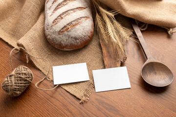 Blank business cards on the wooden background with bread, bakery branding mockup, empty space to...