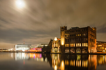 Fototapeta premium Haarlem, The Netherlands, November 19, 2021: night view with light of the Moon of the Spaarne river with the old Droste factory and other industrial heritage