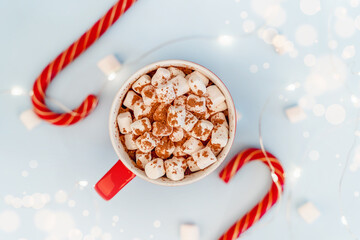 A mug of cocoa with marshmallows and a Christmas garland. A festive concept. Close up, top view