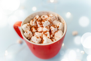 A mug of cocoa with marshmallows and a Christmas garland. A festive concept. Close up, top view